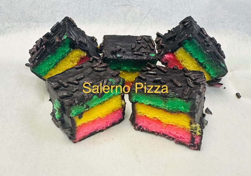 Five rainbow cookies with chocolate frosting and sprinkles, arranged on a white surface.