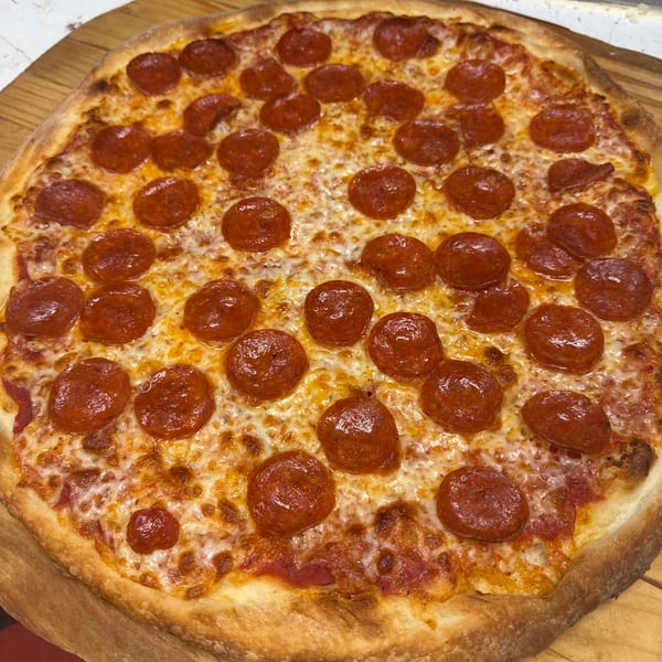 A freshly baked pepperoni pizza with melted cheese and a golden crust on a wooden peel.